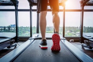 Male feet in sneakers running on the treadmill at the gym. Exerc