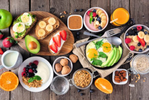 Healthy breakfast table scene with fruit, yogurts, oatmeal, smoo