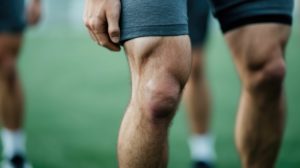 Athlete with Torn Hamstring Receiving Assistance from Teammates During Sports Injury Close up view of sports injury muscle tear and rehabilitation process with blurred background