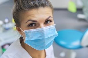 Closeup portrait of smiling female dentist doctor in protective medical mask