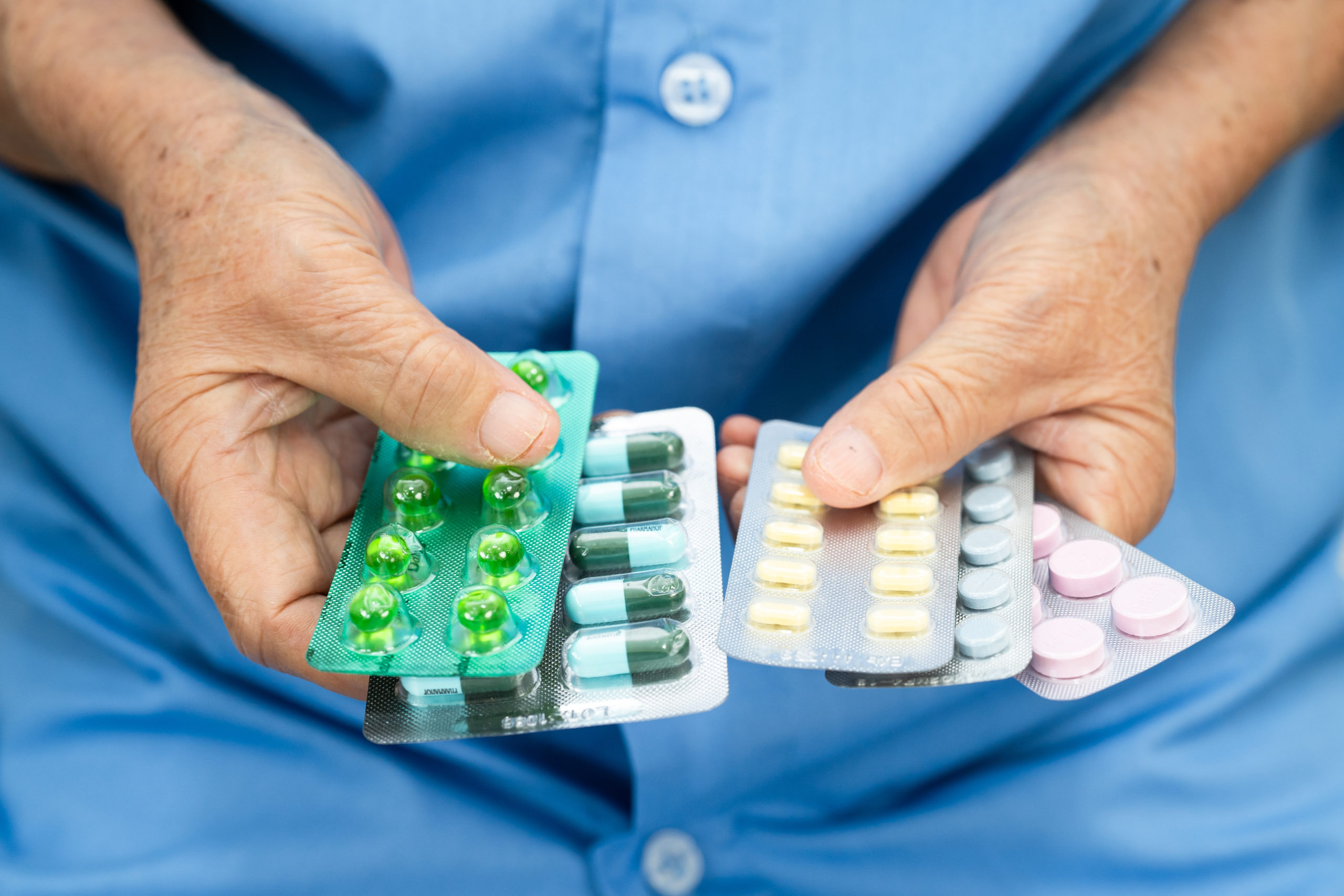 Asian senior woman patient holding antibiotics capsule pills for treatment infection patient in hospital, Pharmacy drugstore.
